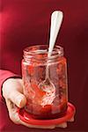 Woman holding almost empty jar of strawberry jam