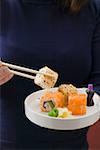 Woman holding inside-out rolls in white dish