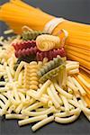 A bundle of spaghetti and various types of coloured pasta