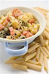 Coloured pasta in strainer, penne beside it