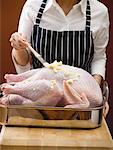 Woman brushing stuffed turkey with butter