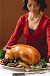 Woman serving roast turkey garnished with fruit