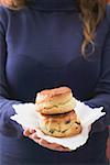 Woman holding two scones on paper napkin