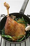Fried goose leg with rosemary in frying pan