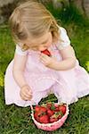Small girl eating strawberries on grass