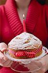 Woman serving birthday cake with bow and candle