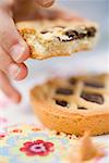 Child's hand holding partly eaten chocolate tartlet