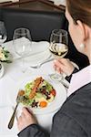 Femme buvant le vin blanc avec une salade au restaurant