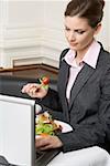 Femme avec ordinateur portable manger salade au restaurant