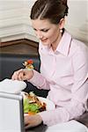 Femme manger salade tout en travaillant sur ordinateur portable dans le restaurant