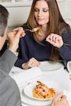 Man offering woman fried prawn in restaurant