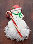 Snowman biscuit and candy cane on wooden background