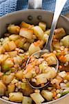 Fried potatoes with vegetables & bacon in frying pan with spoon