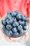 Child's hands holding glass dish of blueberries