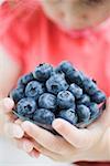 Child holding glass dish of blueberries