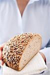 Woman holding sunflower bread (part of a loaf)