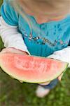 Kleines Mädchen hält Scheibe Wassermelone mit Bissen genommen (overhead)