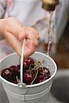 Washing cherries in a bucket under tap