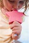 Petite fille mangeant une glace rose sur un bâton