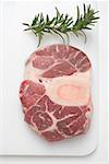 Slice of beef from the leg on chopping board, sprig of rosemary