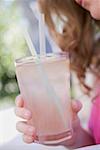 Woman holding a glass of lemonade with straws