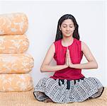 Young woman sitting on the bed in a prayer position