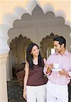 Young woman standing arm in arm with a young man holding a cup of tea