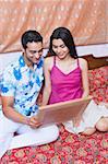 Young couple sitting on a double bed and holding a picture frame