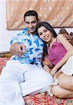 Young couple reclining on the bed and watching television