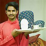 Portrait of a young man carrying a tea tray