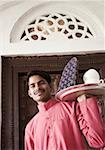 Portrait of a young man carrying a tea tray and smiling