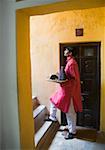 Side profile of a waiter carrying a teapot in a tray and moving up on a staircase