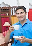 Portrait d'un jeune homme tenant une tasse de thé et une soucoupe