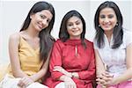 Portrait of a young woman sitting with two mid adult women and smiling