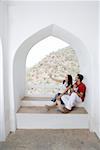Mid adult couple sitting at the balcony of a palace, Neemrana Fort Palace, Neemrana, Alwar, Rajasthan, India