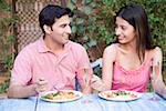 Gros plan d'un jeune couple assis à une table à manger et de manger de la nourriture