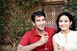 Portrait of a mid adult man sitting with a mid adult woman and holding a champagne flute