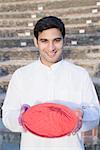 Portrait of a young man holding a plate of powder paint and smiling