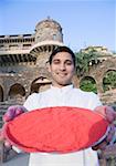 Portrait of a young man holding a plate of powder paint in front of a fort, Neemrana Fort Palace, Neemrana, Alwar, Rajasthan, India
