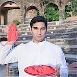 Porträt eines jungen Mannes, hält einen Teller mit Pulver Farbe und zeigt seine Handfläche, Neemrana Fort Palace, Neemrana, Alwar, Rajasthan, Indien