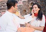 Close-up of a mid adult couple applying powder paint on each other's face