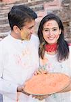 Close-up of a mid adult couple holding a plate of powder paint and smiling