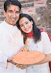 Porträt eines Mitte Erwachsenen Paares holding einen Teller mit Pulver Farbe und Lächeln
