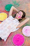 Erhöhte Ansicht einer jungen Frau mit Pulver Farbe auf ihr Gesicht auf dem Boden liegend