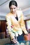 Low angle view of a waitress putting flower vase on a table in a lobby