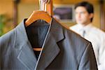 Close-up of a business suit hanging on a clothes rack with a businessman in the background