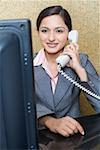 Female receptionist sitting at a hotel reception and talking on the telephone