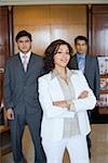 Portrait of a businesswoman standing with two businessmen behind her