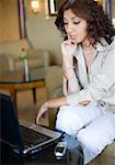 Femme d'affaires à la recherche à un ordinateur portable avec sa main sur son menton