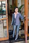 Businesswoman opening the door of a hotel and smiling